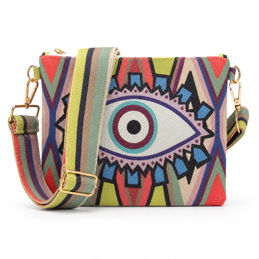 A rectangular crossbody bag featuring a vibrant, multicolored geometric pattern with a large central stylized eye motif. The bag has a matching striped fabric shoulder strap with gold-tone metal hardware, shown against a plain white background.